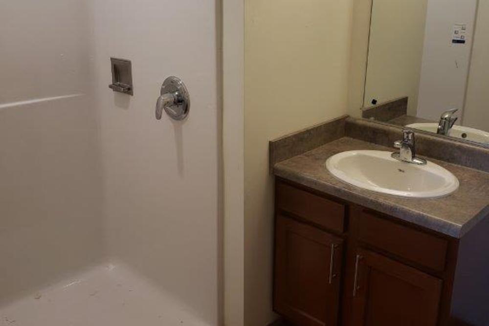 Bathroom with a shower, single sink vanity, and wooden cabinetry at 43 Town Square in Lima, Ohio