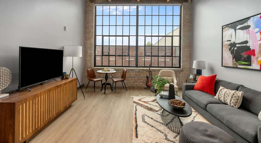 Large couch and a comfortable chair with televison in a model home's living space at Box Board Lofts in Grand Rapids, Michigan