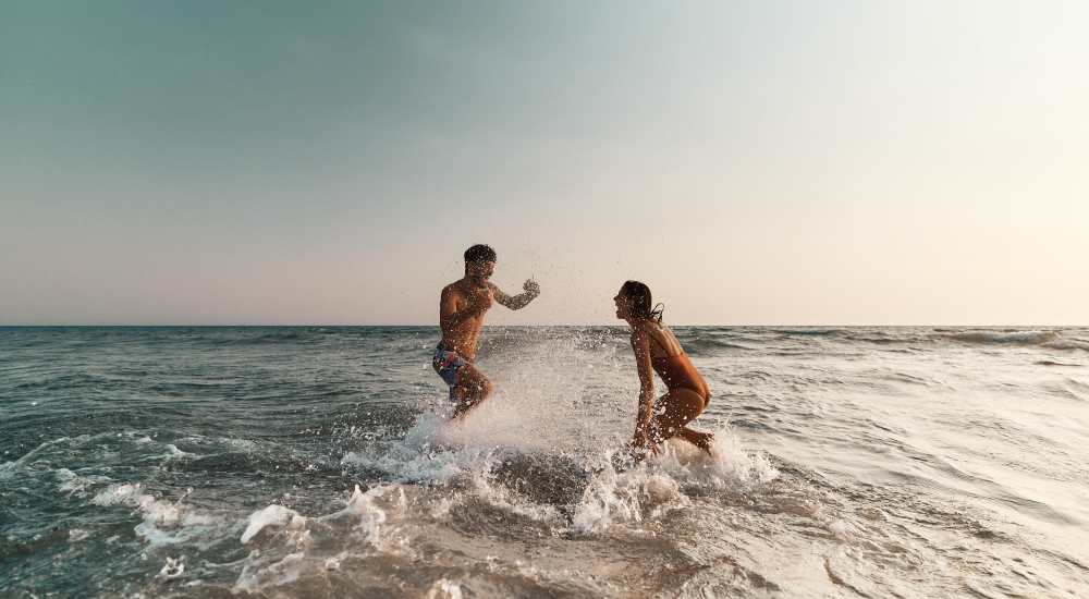 Friends playing in water on beach near The Renaissance in Naples, Florida