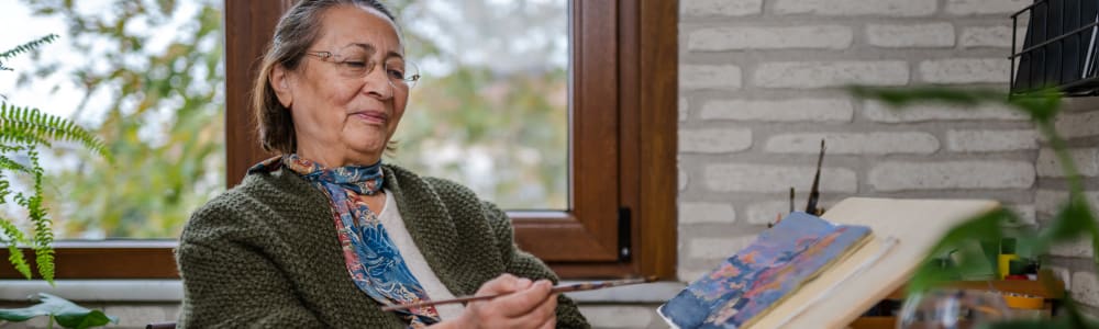 Resident painting on a small canvas in her home