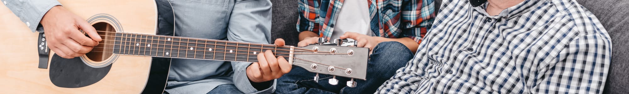 Man playing the guitar for his family at Beech Meadow Apartments