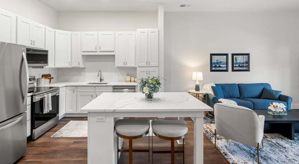 Open kitchen with stainless steel appliances and well-furnished living area at Meriden Place Apartments in Meriden, Connecticut