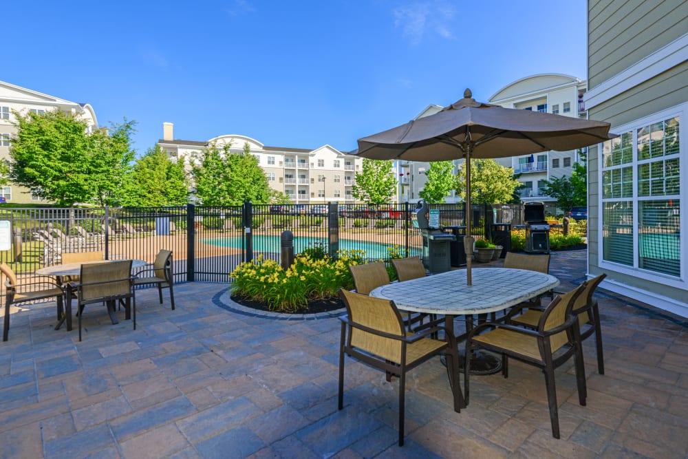 Umbrella covered tables and chairs on pool deck at Sofi Danvers in Danvers, Massachusetts