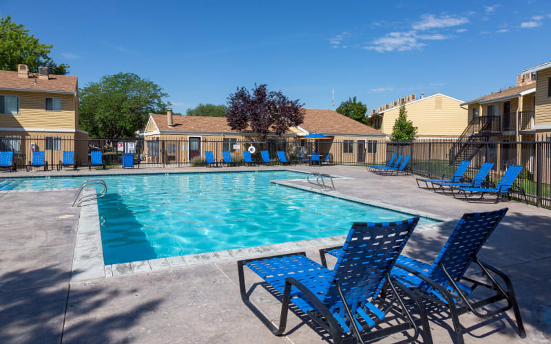 Lounge chairs by the brilliant blue pool at Callaway Apartments in Taylorsville, Utah