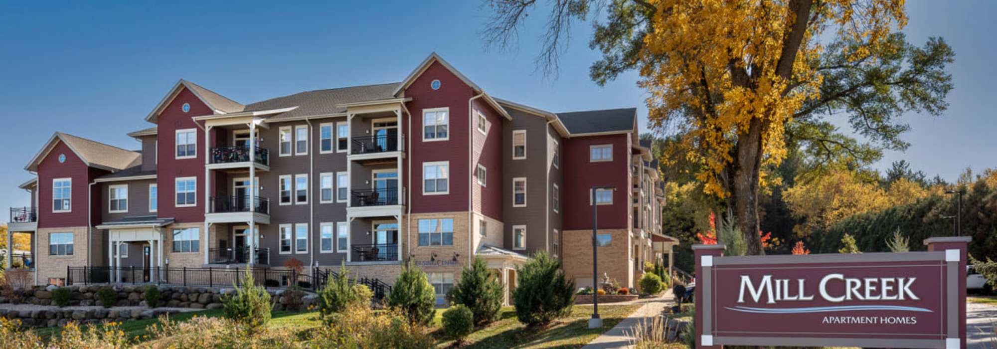Apartment exterior view with property signage at Mill Creek Apartments in Cross Plains, Wisconsin