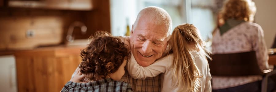 A resident hugging his grandchildren at Welbrook at Bloomington in Bloomington, Illinois