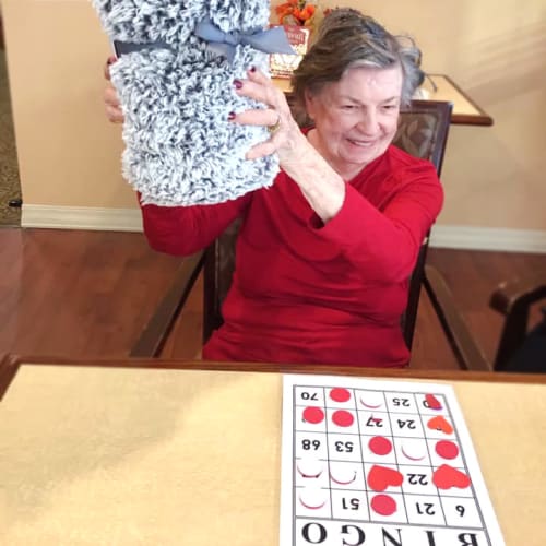 Resident holding a blanket she won at bingo at Oxford Glen Memory Care at Grand Prairie in Grand Prairie, Texas