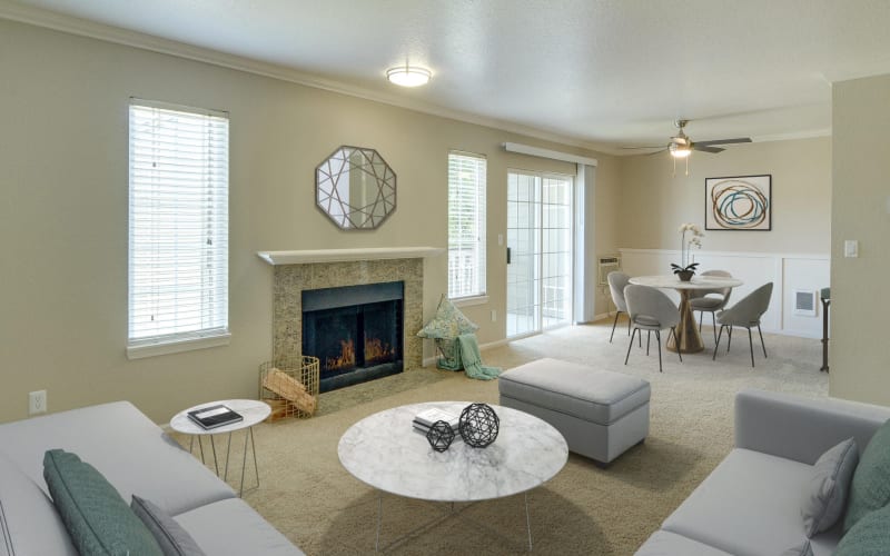 Spacious living room and dining room with a fireplace, ceiling fan and patio access at Carriage House Apartments in Vancouver, Washington