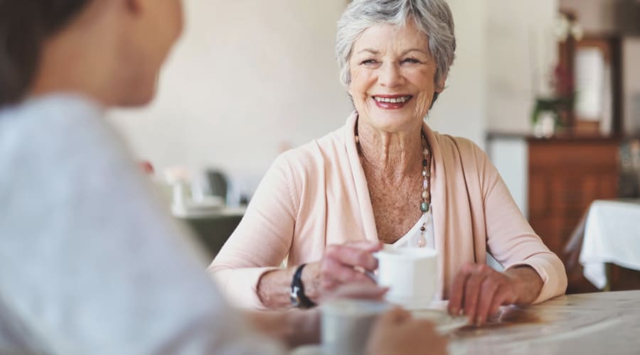 Adult day health senior chatting with a caregiver over tea at Cascade Park Vista Assisted Living in Tacoma, Washington 