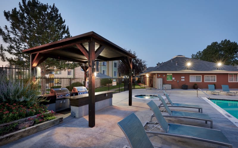 Covered barbecue area near the swimming pool at dusk at Alton Green Apartments in Denver, Colorado