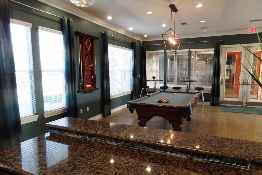 Community clubhouse with kitchen area, game area and large windows at The Abbey at Stone Oak in San Antonio, Texas