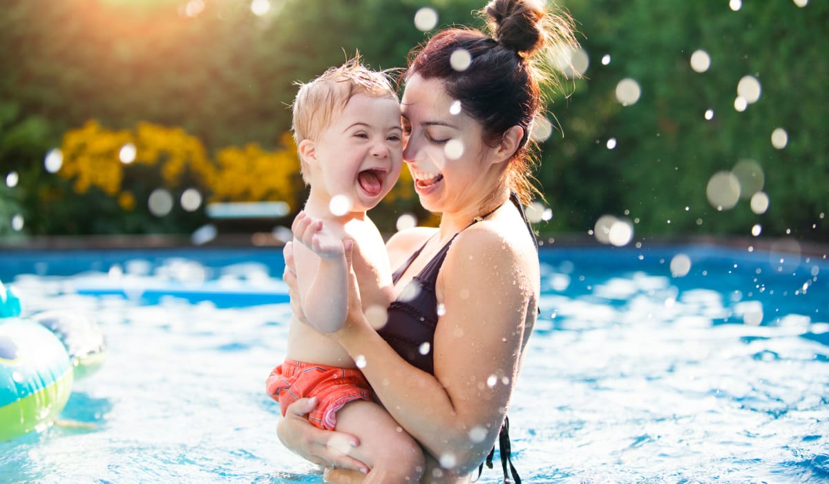 A woman holding a child in the pool at The Woodlands Apartment Homes in Florence, Alabama