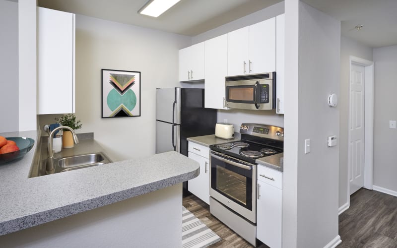 Renovated kitchen with stainless steel appliances and white cabinets at Bear Valley Park in Denver, Colorado