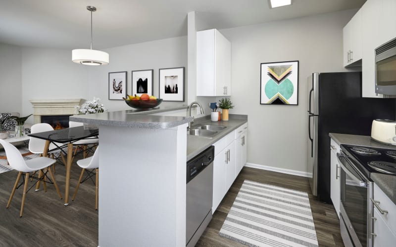 Renovated white kitchen with hardwood-style floors overlooking the living room at Bear Valley Park in Denver, Colorado