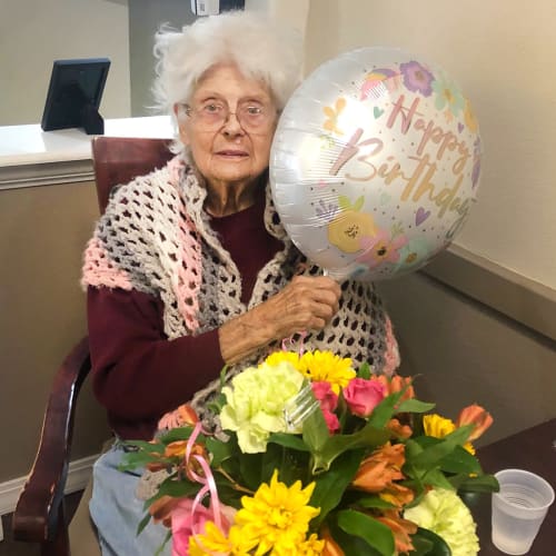 Resident celebrating her birthday with gifts of flowers and balloons at Madison House in Norfolk, Nebraska