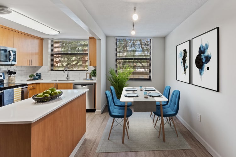 Model dining room and kitchen with stainless-steel appliances and an island at Bull Run Apartments in Miami Lakes, Florida