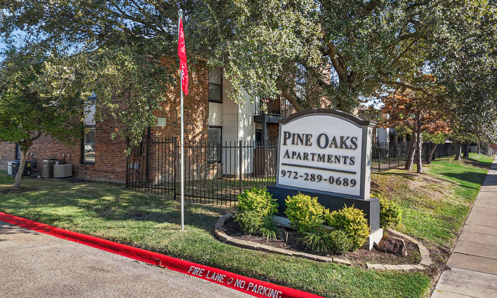 Property signage board at Pine Oaks Apartments in Mesquite, Texas