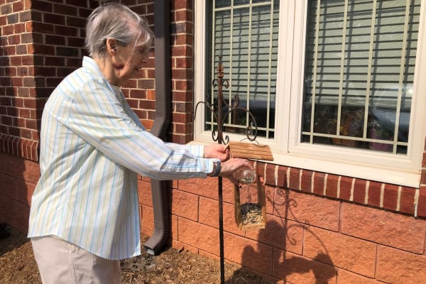 resident filling a bird feeder at The Foothills Retirement Community in Easley, South Carolina.