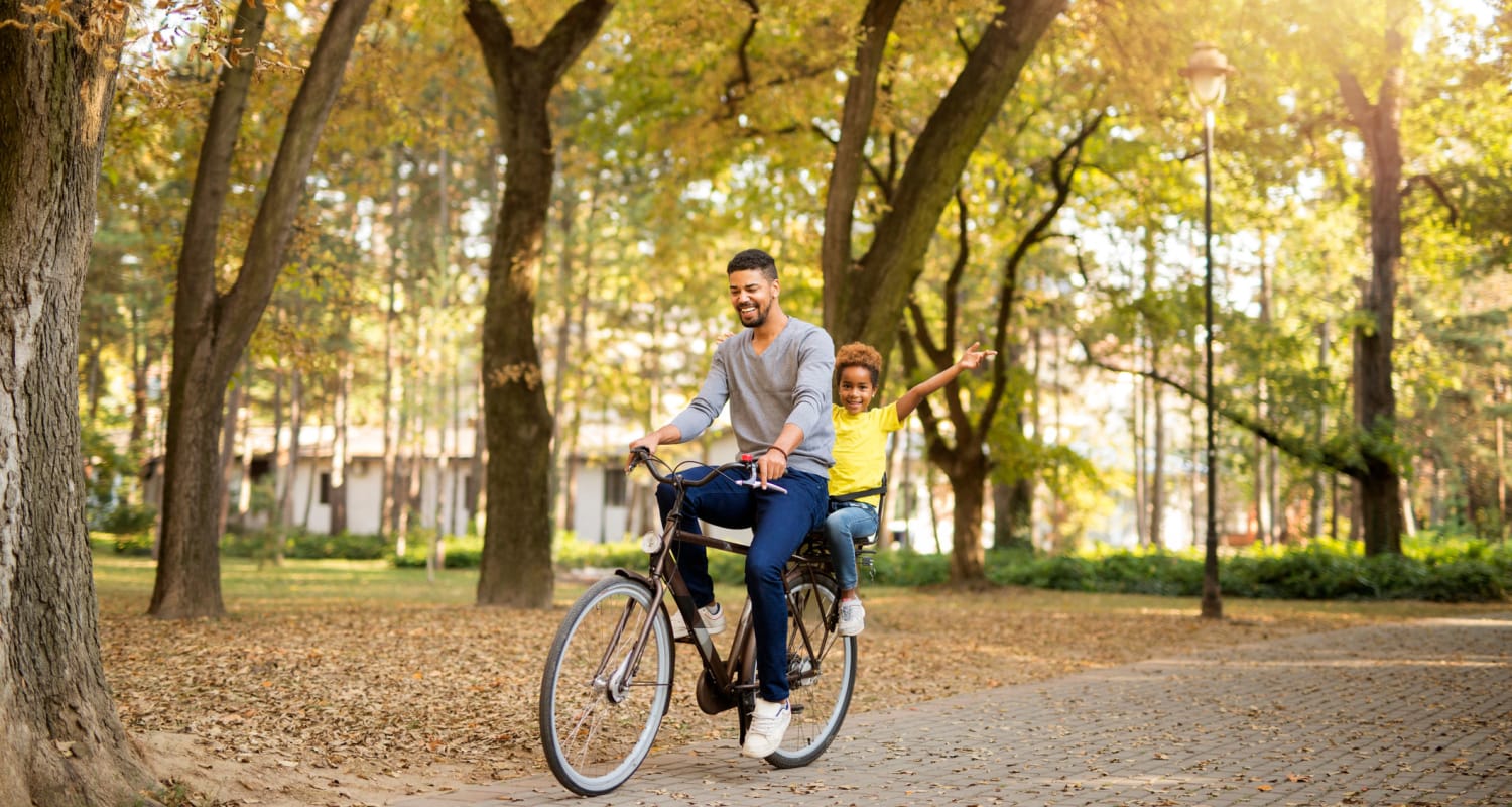 A resident riding bicycle with his child in a park at West Hartford Collection in West Hartford, Connecticut