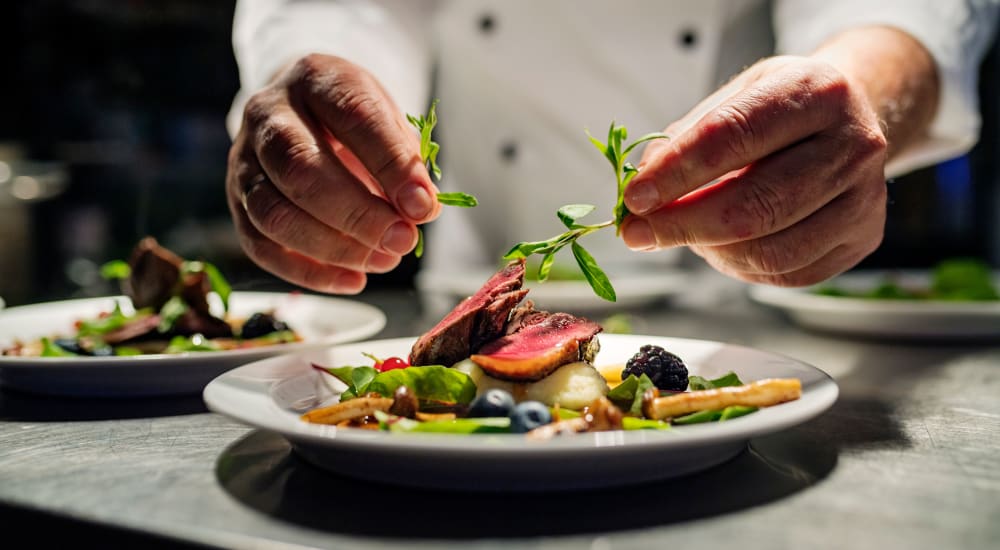 A chef topping a dish with garnish at The Springs at Lake Oswego in Lake Oswego, Oregon