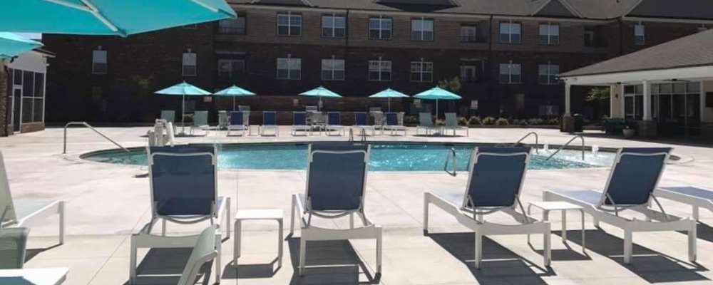 Deck chairs and turquoise umbrella beside the pool at Keystone At Walkertown Landing in Walkertown, North Carolina