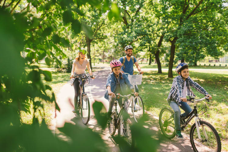 Family riding bikes through a park near Merrimack, New Hampshire near London Court Apartments