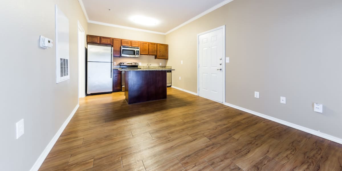 Open living space with kitchen island and wood flooring at Marquis at Barton Trails in Austin, Texas