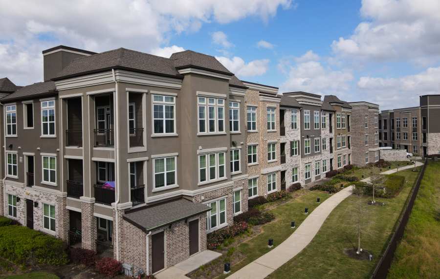 Exterior view of the community with green lawn and balcony view at Orleans at Fannin Station in Houston, Texas