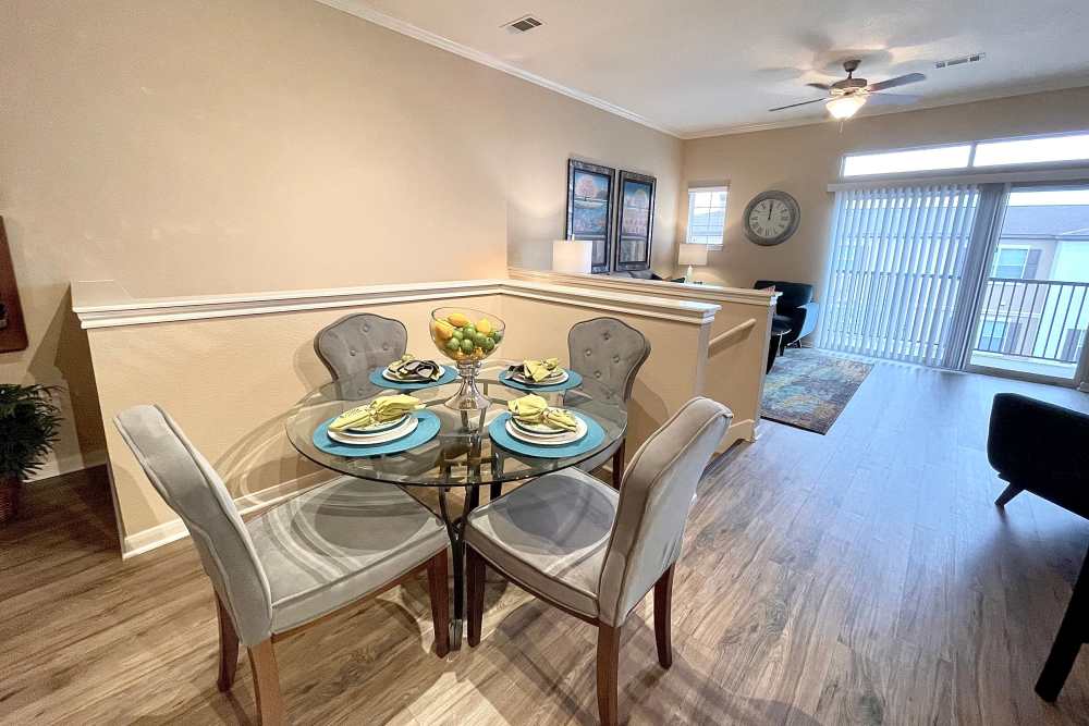 Open style dining area with access to living room and patio with wood-style flooring at The Abbey at Stone Oak in San Antonio, Texas
