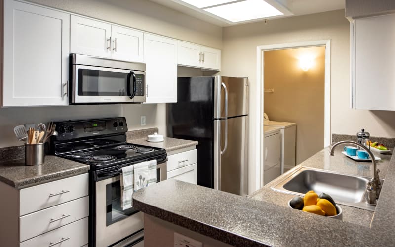 Renovated kitchen with white cabinets at Sierra Del Oro Apartments in Corona, California