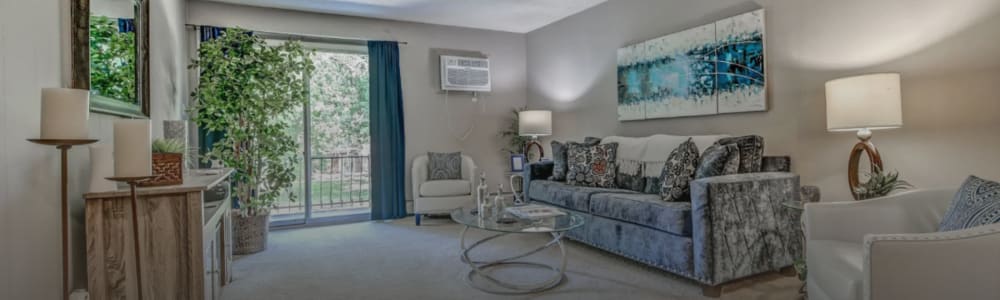 Living room with plush carpting, large couch and window at Park West Apartments in Griffith, Indiana