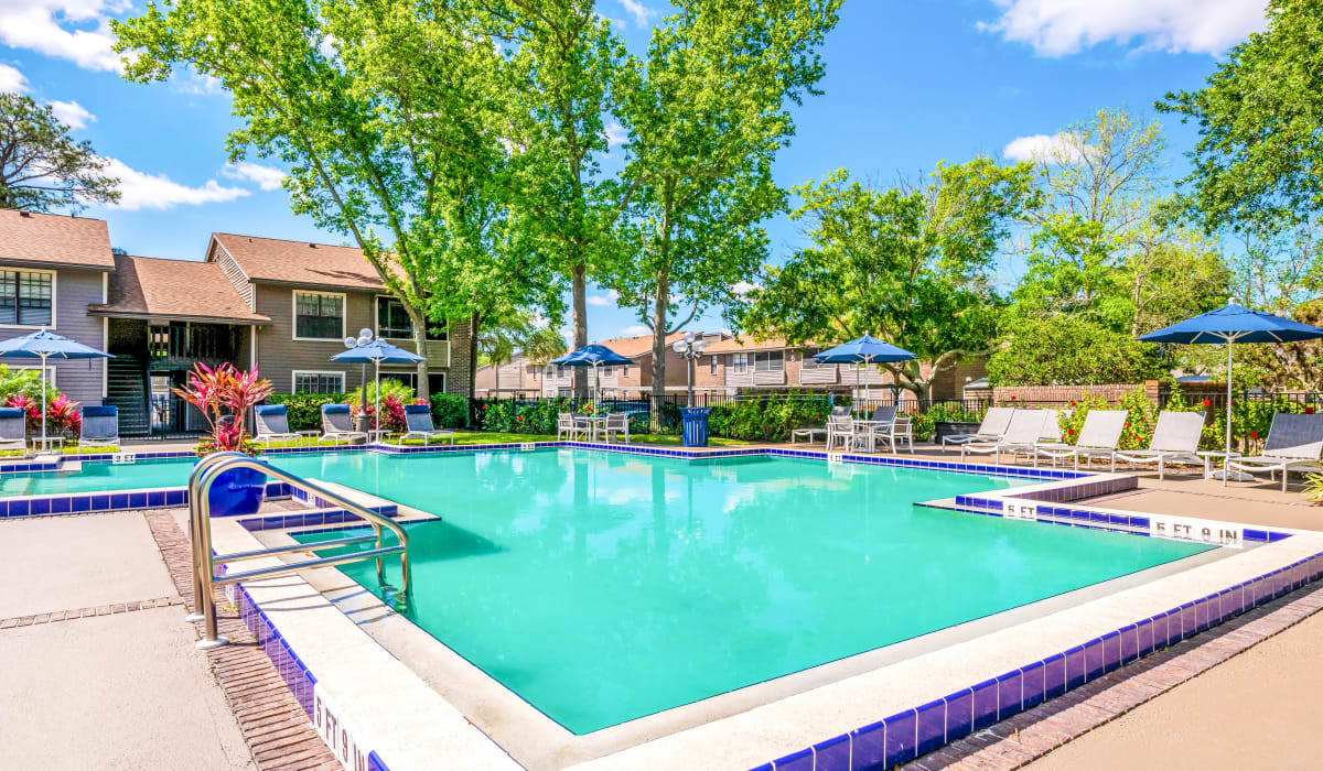 Pool with lounge chairs and umbrellas at Bentley Green Apartment Homes, Jacksonville, Florida