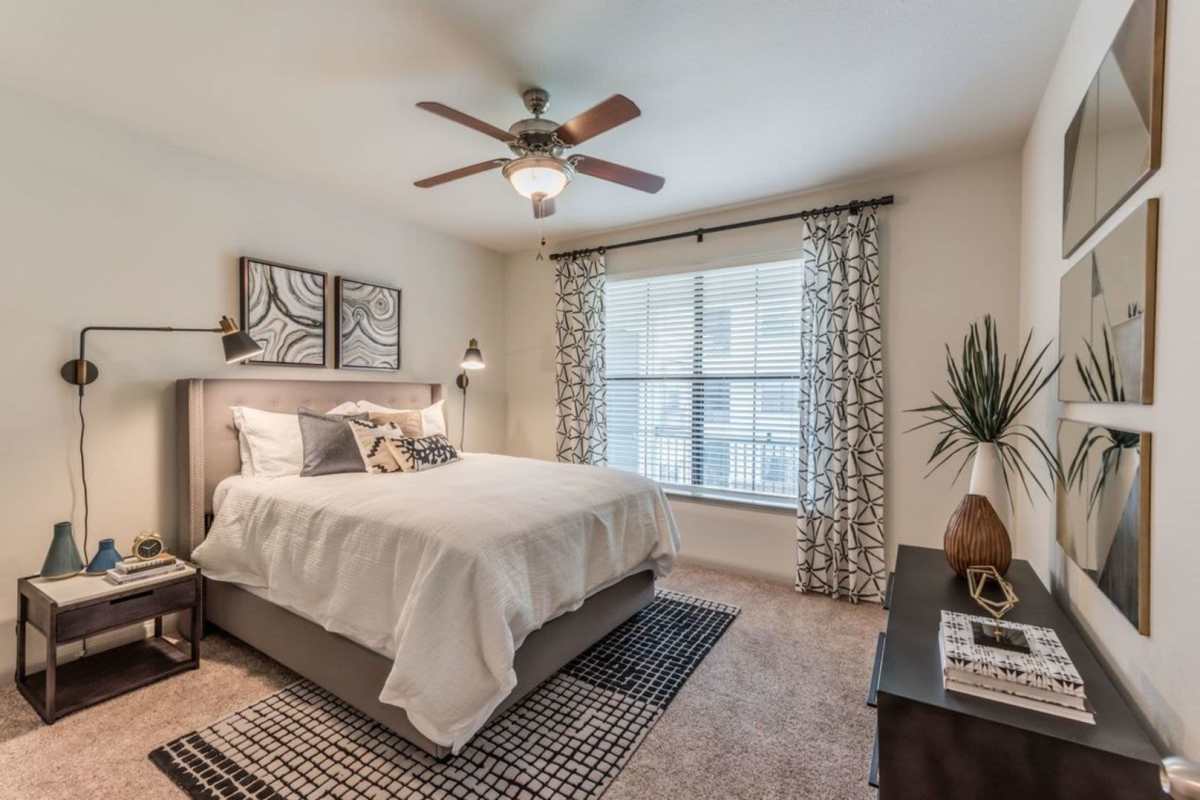 Bright bedroom with large windows and ceiling fan at Villas At Bunker Hill, Houston, Texas