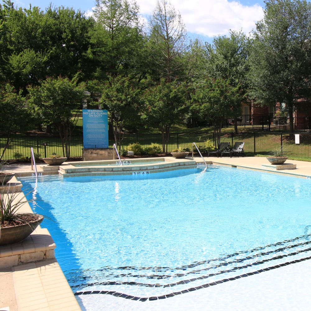 Swimming pool surrounded by mature trees at Oaks Estates of Coppell in Coppell, Texas