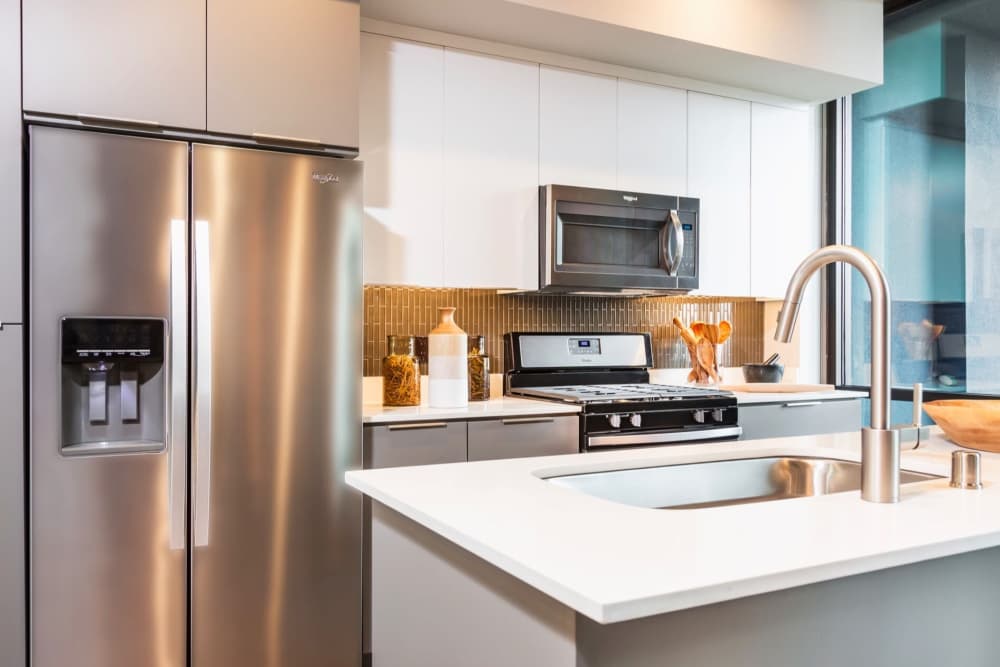 Kitchen with refrigerator, stainless-steel appliances and range at The George Apartment Homes in Anaheim, California