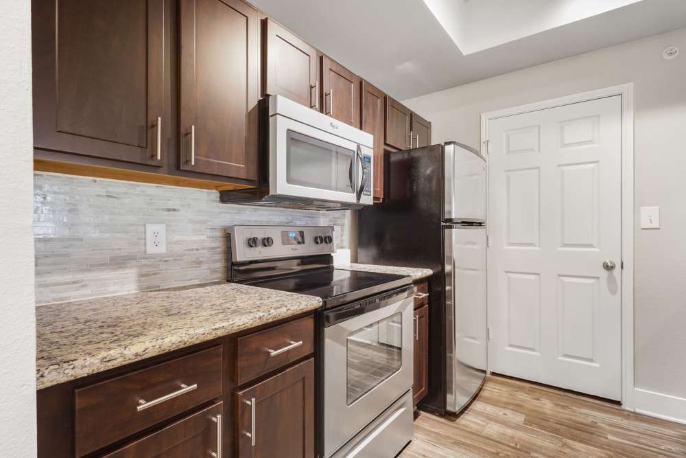 Kitchen with wood cabinet and stainless-steel appliances at Carrara at Cole in Dallas, Texas