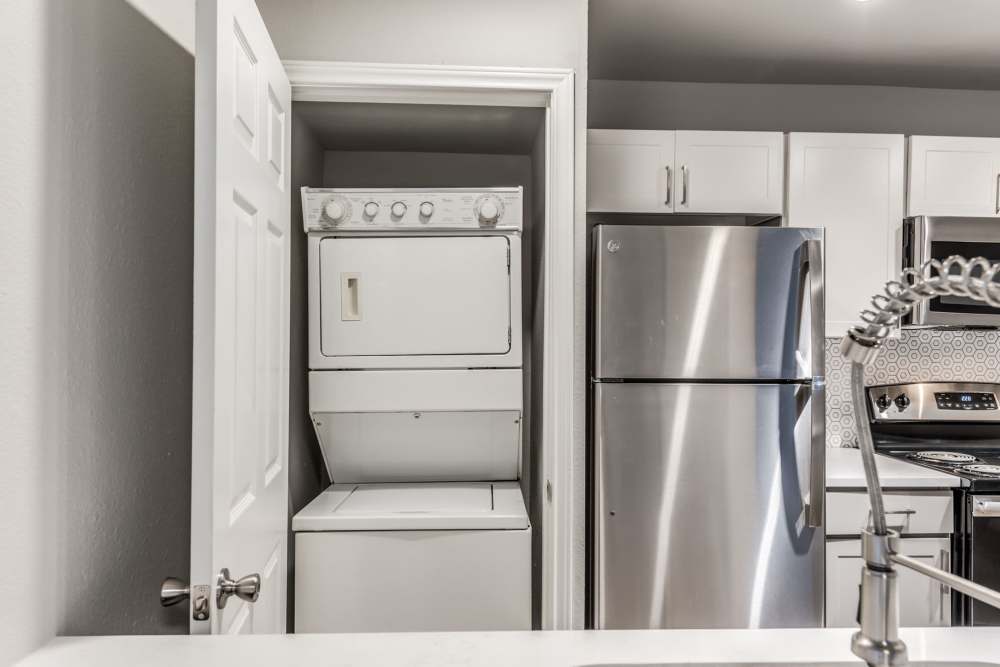 Refrigirater and stacked washer and dryer in kitchen at Warwick at Westchase in Houston, Texas