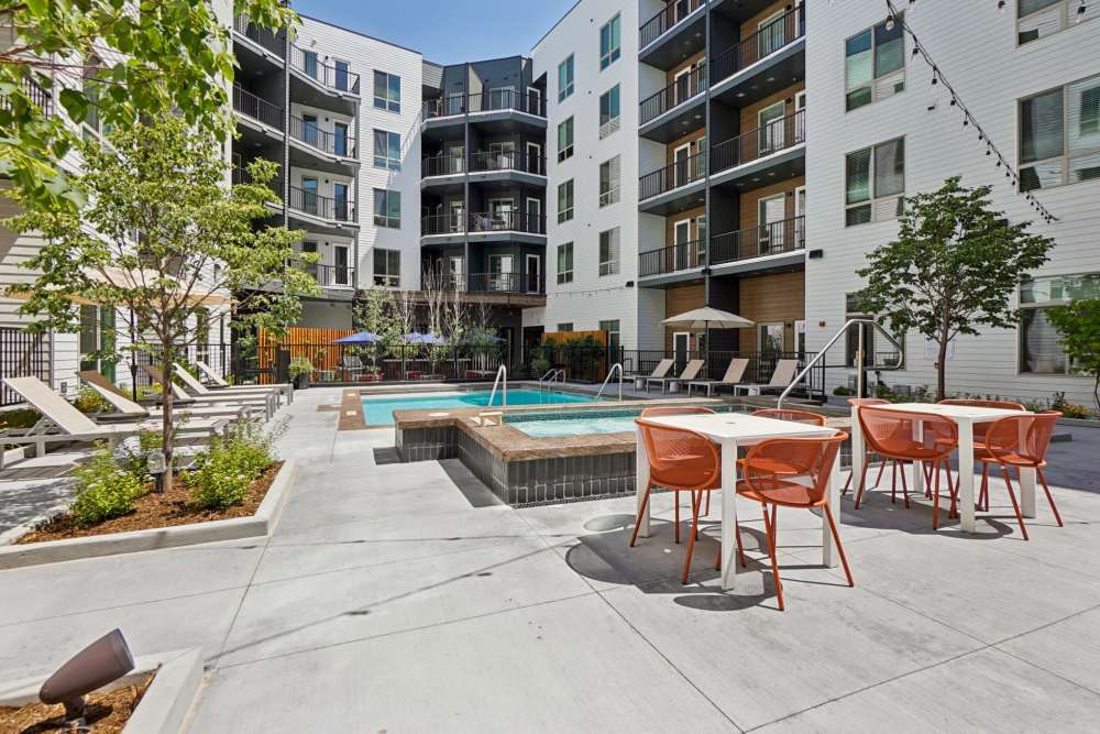 Modern apartment courtyard with pool, hot tub, and lounge area at Tempo at Nine Mile Station in Aurora, Colorado