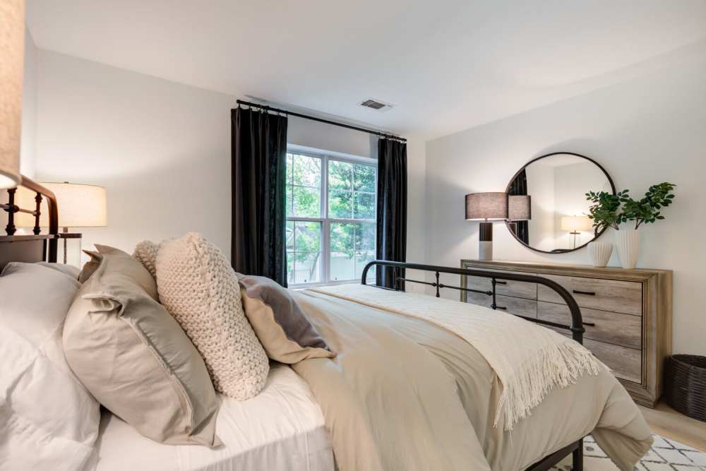 Cozy bedroom with large window, soft bedding, decorative pillows, and modern furniture accents at J Harbor Park at North Point in Reston, Virginia
