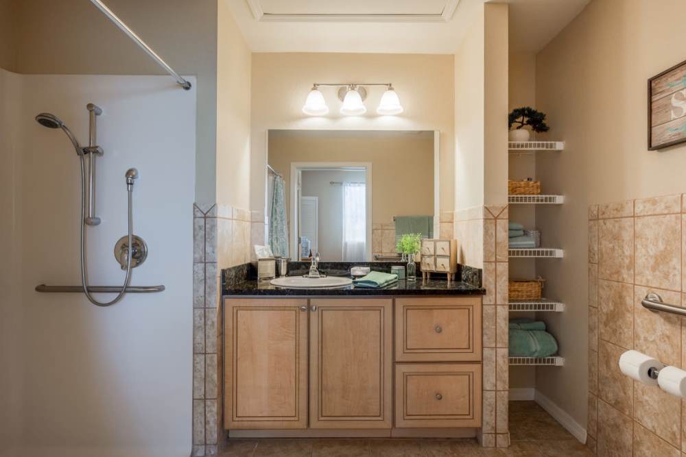 Modern bathroom with vanity light, mirror, sink, storage space and shower at Grand Villa of Ocala in Ocala, Florida