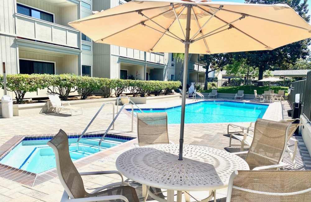 Patio umbrella by swimming pool at Springwood Apartment Homes in Los Altos, California