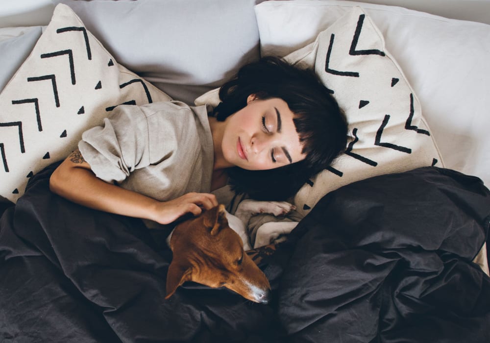 Resident woman cuddling her puppy in bed at the pet-friendly apartments at Glass Creek in Mt Juliet, Tennessee