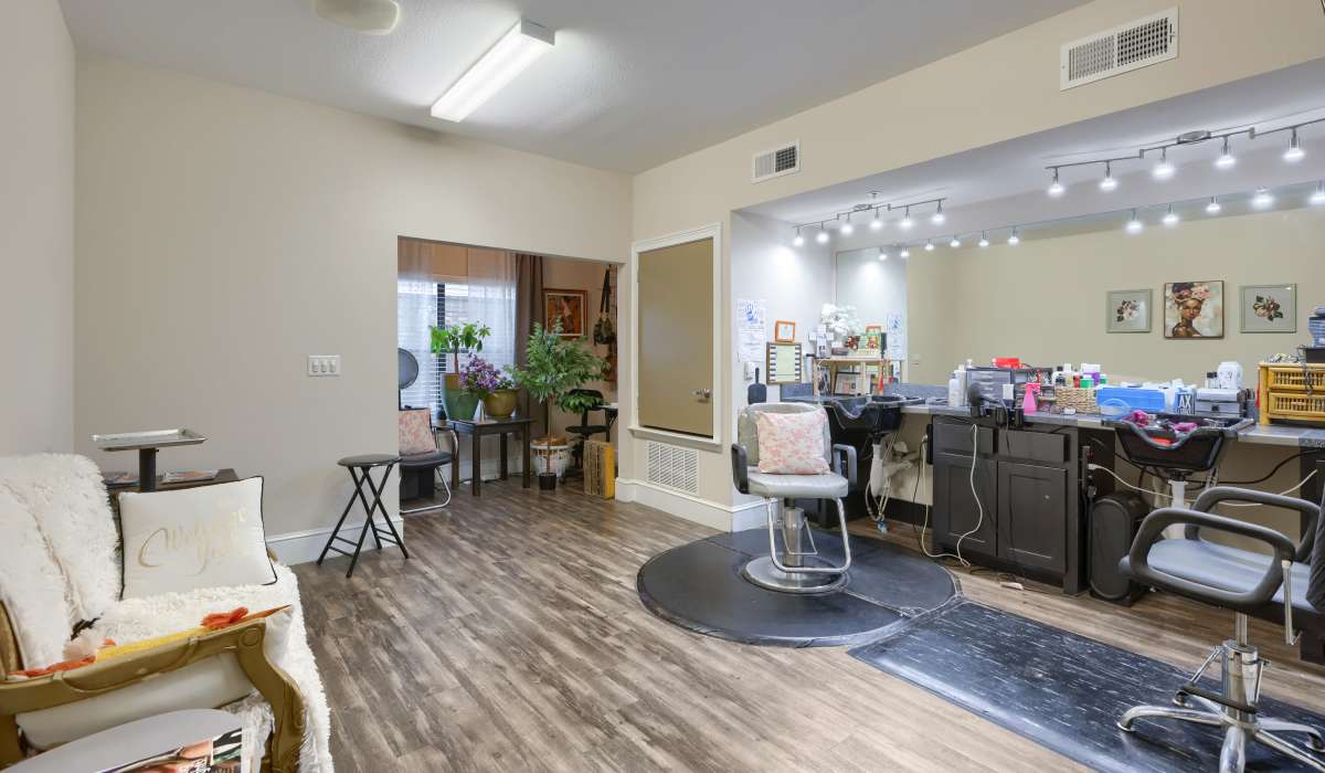 Stylish salon with wood-style flooring and modern styling chairs, vibrant plants enhancing the atmosphere at Lindbergh Parc Senior Apartments in Fort Worth, Texas