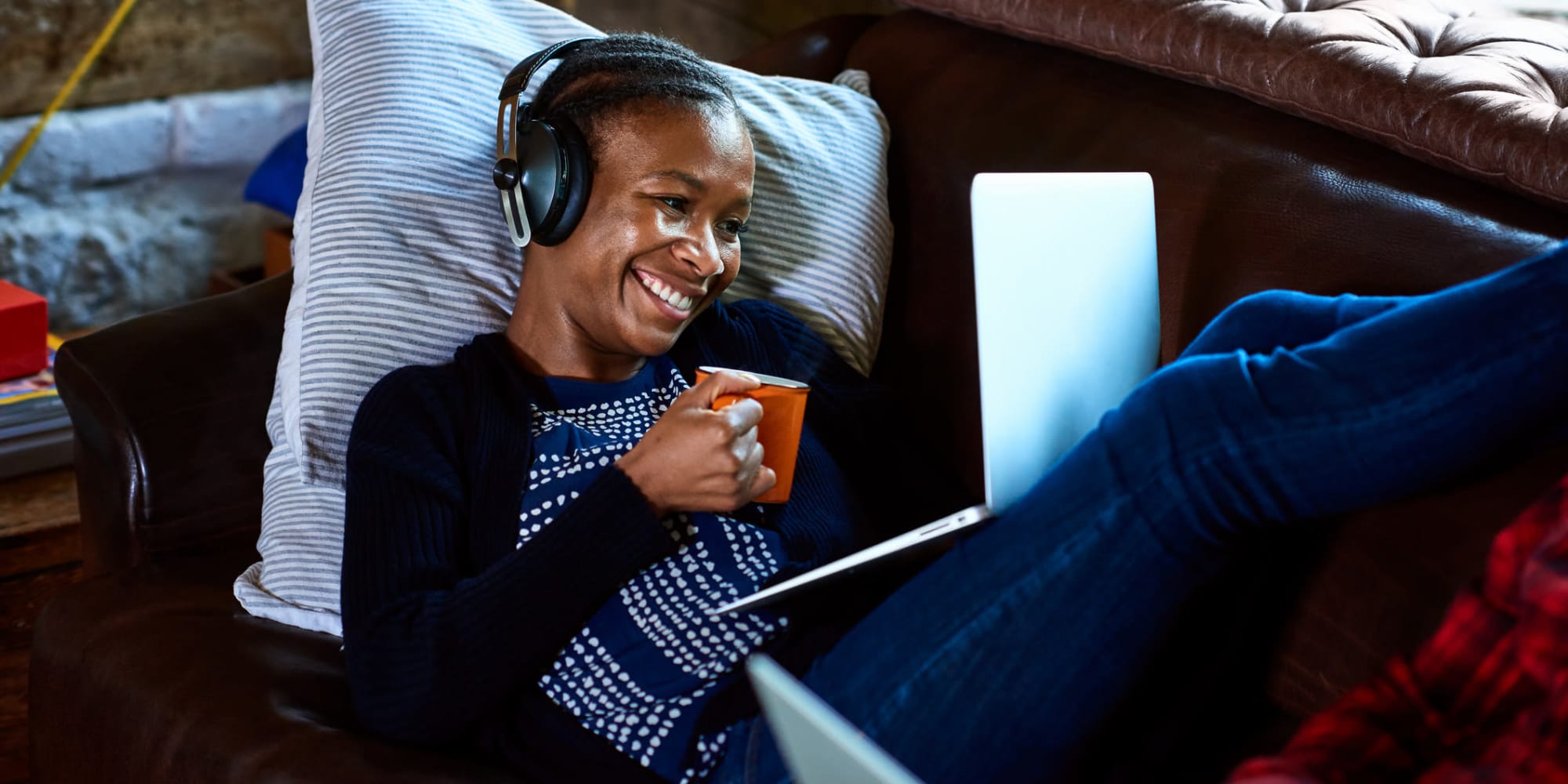 A woman on her couch with her laptop and a cup of coffee at Paragon Apartments in Lawton, Oklahoma