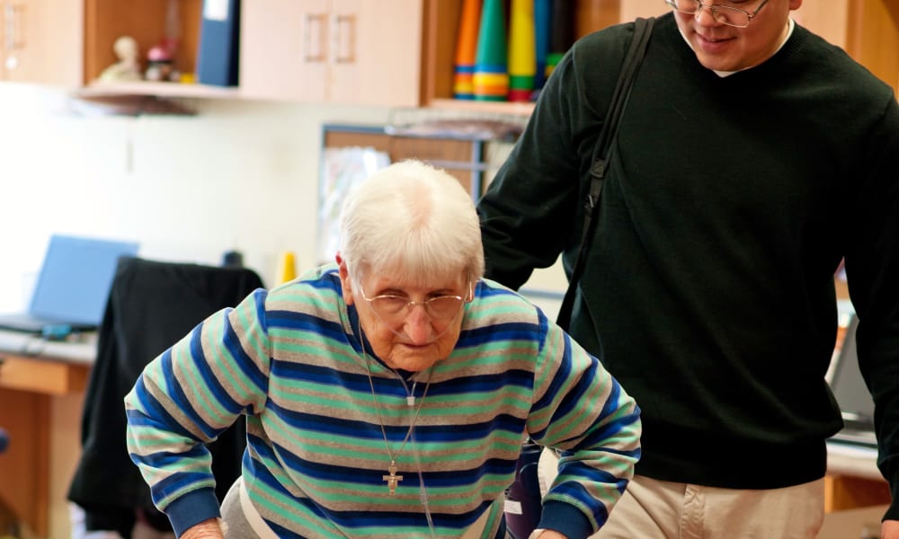 Caretaker assisting a mobility-challenged resident with a walker at Fair Oaks Health Care Center in Crystal Lake, Illinois