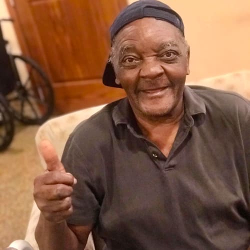 seated resident smiling and giving a thumbs up at Oxford Glen Memory Care at Carrollton in Carrollton, Texas