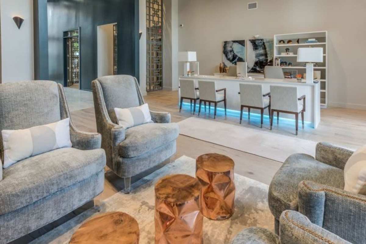 A modern lounge area featuring two comfortable armchairs and decorative side tables made of polished metal at Villas At Bunker Hill, Houston, Texas