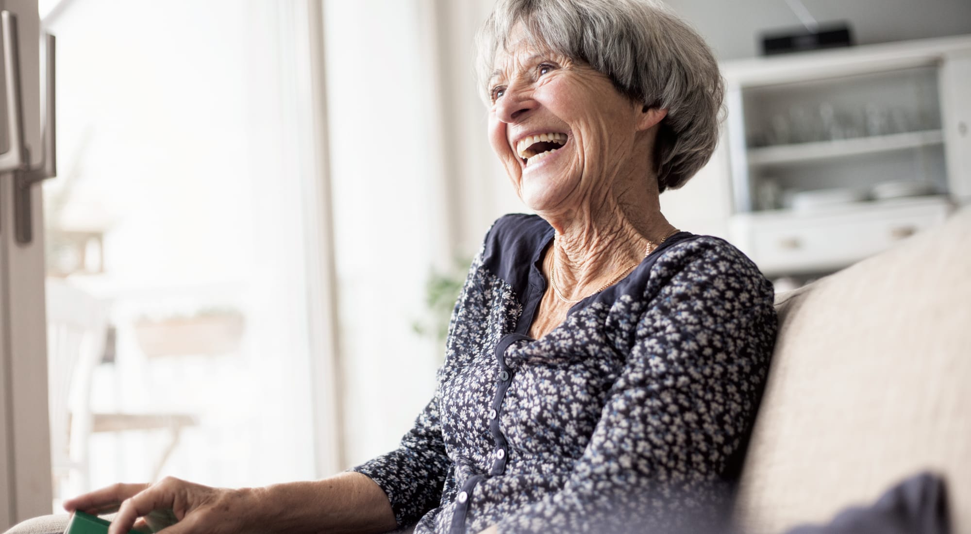 Woman sitting on the couch laughing at Anthology Senior Living in Chicago, Illinois