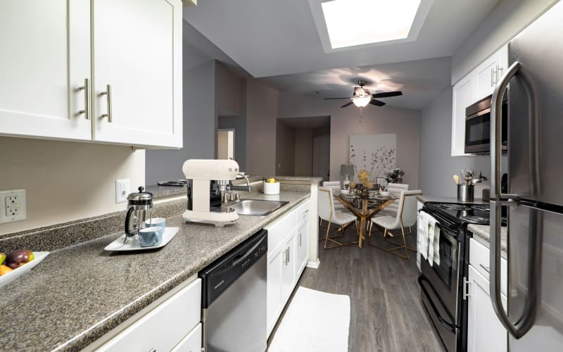 Ample counter space in a kitchen overlooking a dining room at Sierra Del Oro Apartments in Corona, California