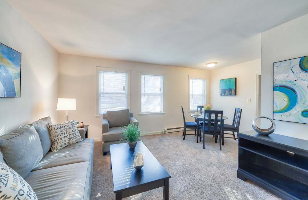 Cozy living area with plush carpet, modern furniture, and dining table at Fordleigh Apartments in Baltimore, Maryland